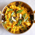 A bowl of moong dal khichdi, a soft lentil and rice porridge garnished with curry leaves and ghee